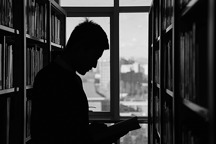 guy reading in library black and white